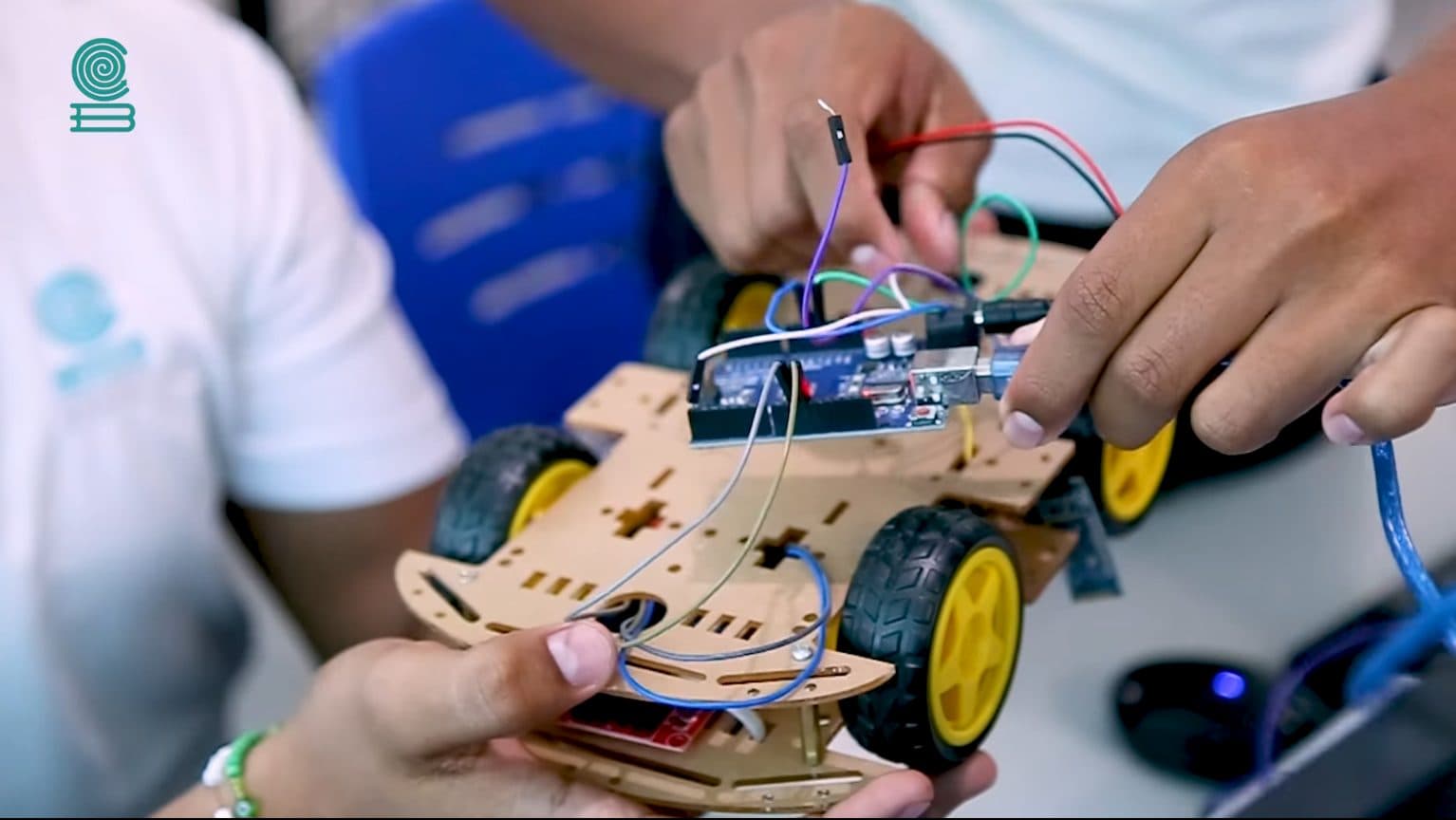 Estudiante sosteniendo un carrito robot armado con Arduino